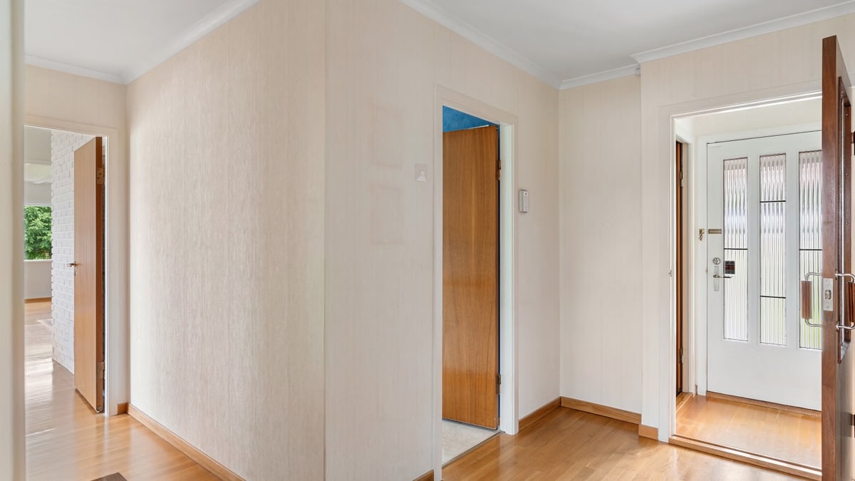 Bright hallway with wooden floors and open doors in a modern home interior.
