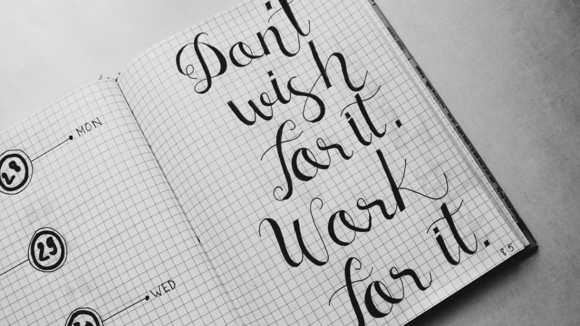 Close-up of motivational calligraphy on grid paper, inspiring message for productivity.