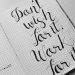 Close-up of motivational calligraphy on grid paper, inspiring message for productivity.